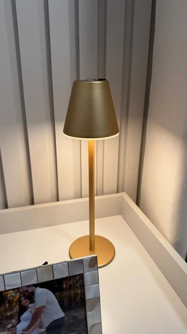 Lâmpada de mesa dourada com acabamento fosco e difusor cônico.