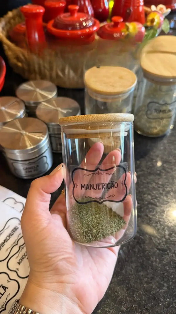 Pote de vidro com tampa de cortiça, cheio de especiaria ou erva verde.